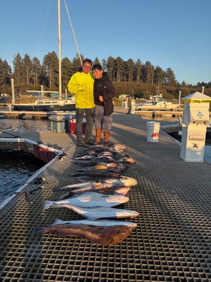 Two KYS guests on the dock with halibut and other fish from their trip laid out in front of them